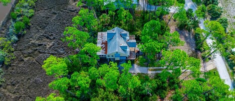 A house surrounded by dense greenery and a river.