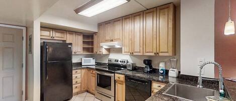 A kitchen with wooden cabinets, a black refrigerator, a microwave, a stove, and a sink.