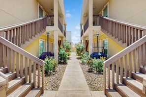 A corridor with a central walkway flanked by two buildings with balconies and wooden railings. - Escape Condominiums #2 (South Padre Island)