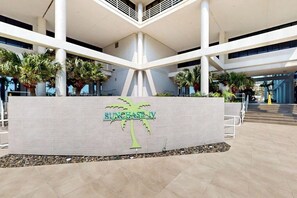Un bâtiment moderne doté d’un atrium central, de palmiers et d’une enseigne indiquant « SUNCHASE IV ».