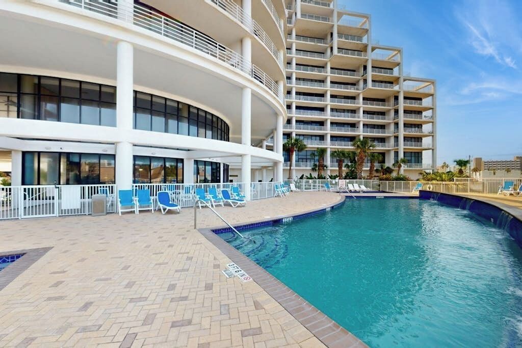 Un hôtel doté d’une piscine, de chaises longues et d’un bâtiment à plusieurs étages.