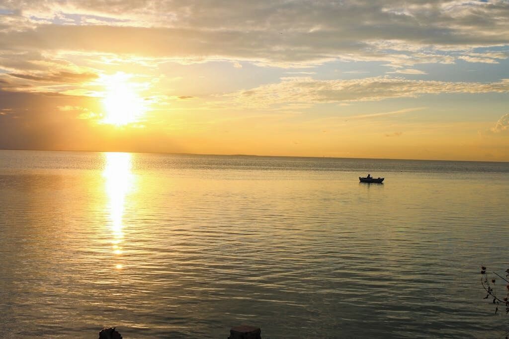 Una masa de agua tranquila con un barco a lo lejos y cielo despejado.