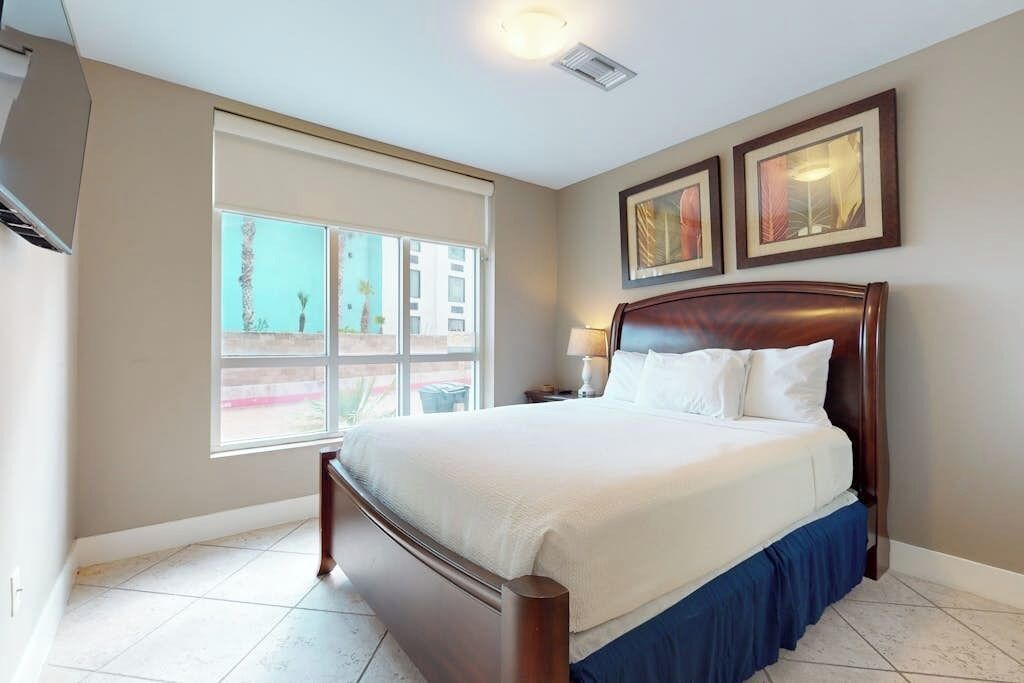 Habitación de hotel con una cama grande, una ventana con vistas y obras de arte enmarcadas en la pared.
