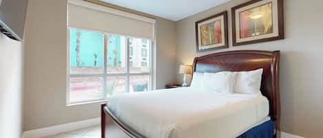 Habitación de hotel con una cama grande, una ventana con vistas y obras de arte enmarcadas en la pared.