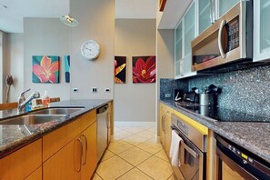 Una cocina moderna con encimeras de granito, electrodomésticos de acero inoxidable y obras de arte en las paredes.