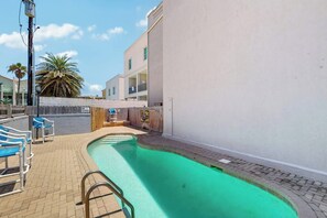 A swimming pool with a diving board, lounge chairs, and a wooden deck. - Coronado Condominiums #102 (South Padre Island)