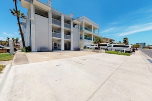 A multi-story building with a parking area in front. - Coronado Condominiums #102 (South Padre Island)