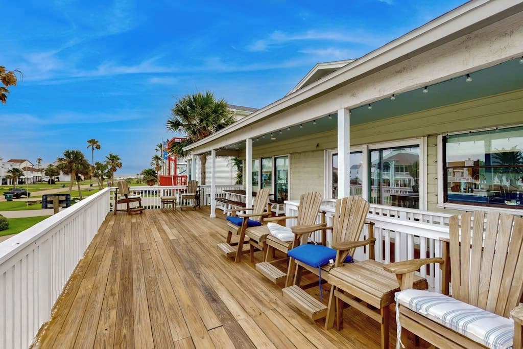 A wooden deck with outdoor seating and a view of the ocean.