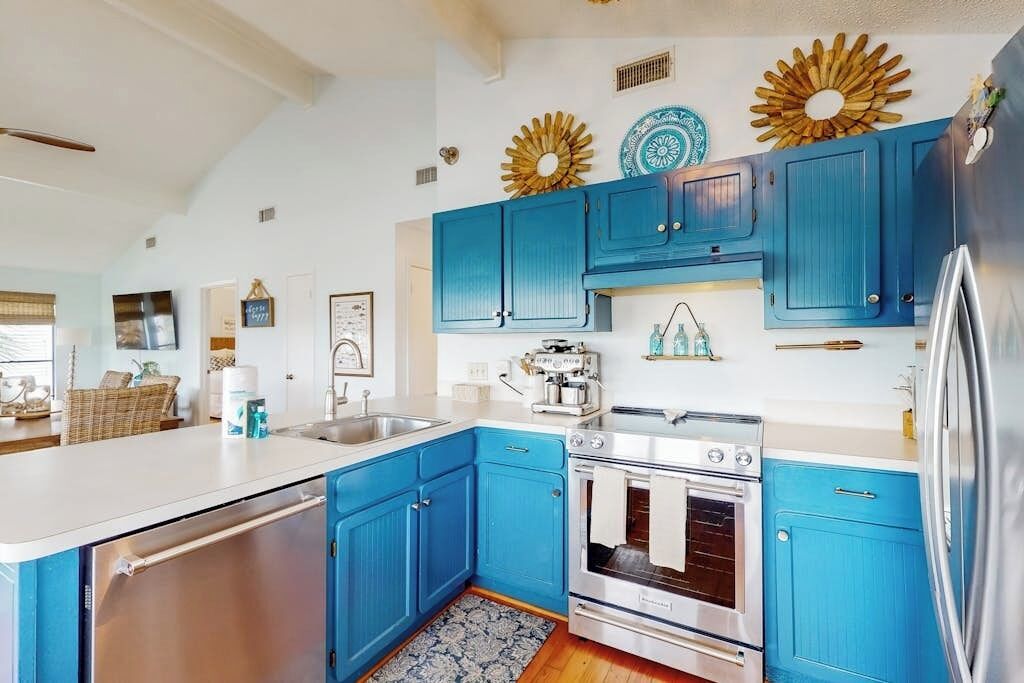 Una cocina con armarios azules, un refrigerador de acero inoxidable y un horno empotrado.