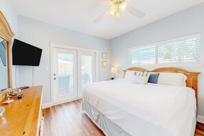 A bedroom with a bed, a television, a desk, and a ceiling fan. - Another Day In Paradise (Port Aransas)