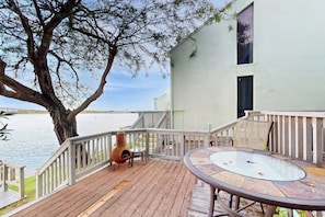 A deck with a glass-top table and chairs, overlooking a body of water. - Puente Vista 105 - Waterfront, Dock & Fire Pit (Corpus Christi)