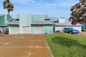A residential building with a garage, a driveway, and a parked car. - Puente Vista 105 - Waterfront, Dock & Fire Pit (Corpus Christi)
