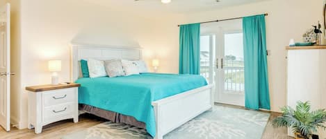 A bedroom with a bed, nightstands, a ceiling fan, a window with curtains, and a view outside.