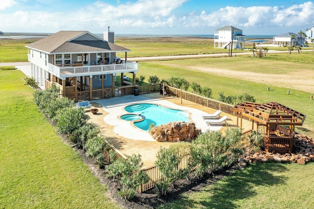 A large house with a swimming pool, a deck, and a view of the ocean.
