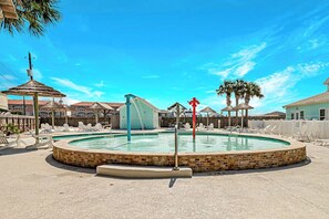Ein runder Pool mit einer Springbrunnen, umgeben von Liegestühlen und einem Holzzaun.