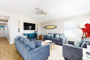 A living room with a sofa set, a television, and a decorative wall piece. - Classy Bum - Covered Patio & Alfresco Dining (Port Aransas)