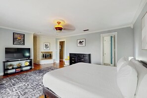 Ein Schlafzimmer mit einem Bett, einem Fernseher, einem Kamin und einer Tür.