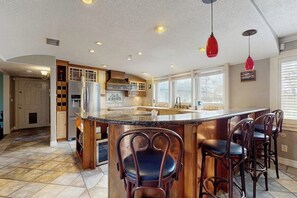 Una cucina con una grande isola, sgabelli da bar e illuminazione a sospensione.