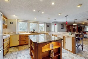 A spacious kitchen with granite countertops, wooden cabinets, and a central island. - Sunshine Shores - Pool Table, Yard & Dogs OK (Corpus Christi)