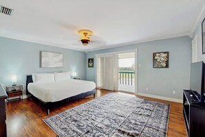 A bedroom with a bed, a ceiling fan, a window with blinds, a door leading to a balcony, and a television. - Sunshine Shores - Pool Table, Yard & Dogs OK (Corpus Christi)