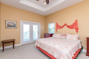 A bedroom with a bed, a bench, a door, and a window. - Royal Sands Beauty - Walk to Beach, Pool Access (Port Aransas)