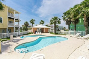 Una piscina amb gandules, una zona tancada i un edifici amb balcons.