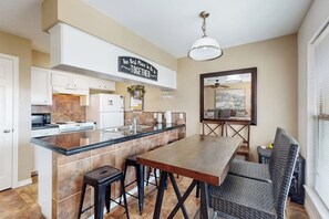 A modern kitchen with a central island, bar stools, and a dining table. - Pirate's Crossing #B6 (Corpus Christi)