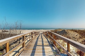 A wooden boardwalk leading to a beach with clear skies. - Oceans 11th - Steps to Beach, Near Shops (Port Aransas)