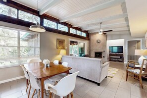 A spacious living area with a dining table, sofa, and fireplace. - Zen Live Oak Living - Fire Pit, Lanai & Dogs OK (Rockport)