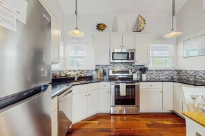 Eine moderne Küche mit Edelstahlgeräten, weißen Schränken und einer Backsplash mit Fischgrätmuster.