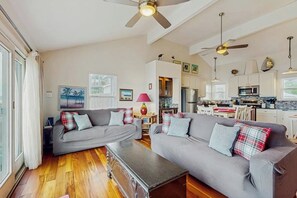 Ein großzügiger Wohnbereich mit zwei grauen Sofas, einem Couchtisch und Deckenventilatoren.