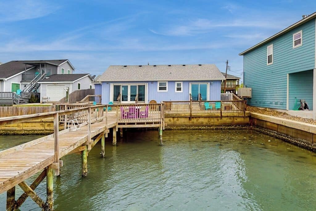 Une propriété située au bord de l’eau, dotée d’un quai, d’une petite jetée et d’une maison à l’extérieur bleu.