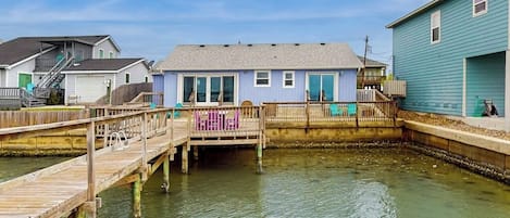 Une propriété située au bord de l’eau, dotée d’un quai, d’une petite jetée et d’une maison à l’extérieur bleu.