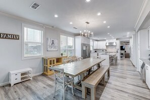 A spacious kitchen with a long dining table, white cabinetry, and a 'FAMILY' sign on the wall. - Inkies Retreat - Waterfront Home with Swim Spa (Rockport)