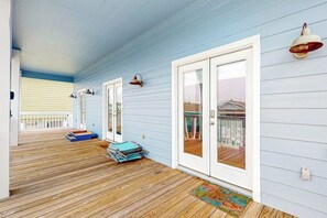 Eine überdachte Veranda mit Holzboden, Glastüren in weißen Rahmen und einer blauen Außenwand.