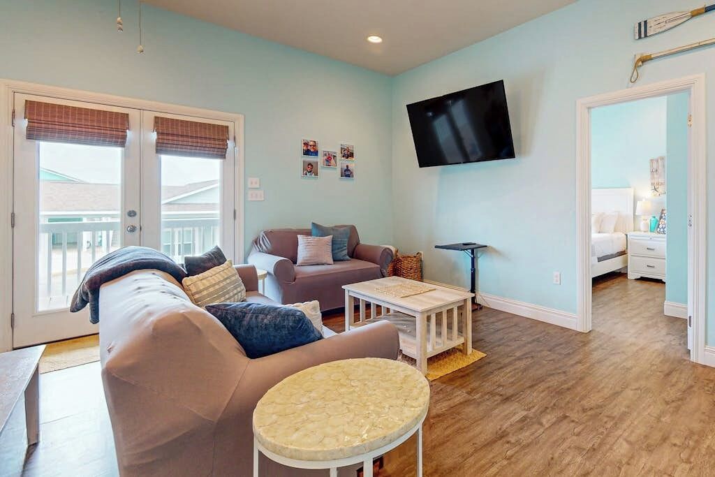 A living room with a sofa, a round table, and a television mounted on the wall.