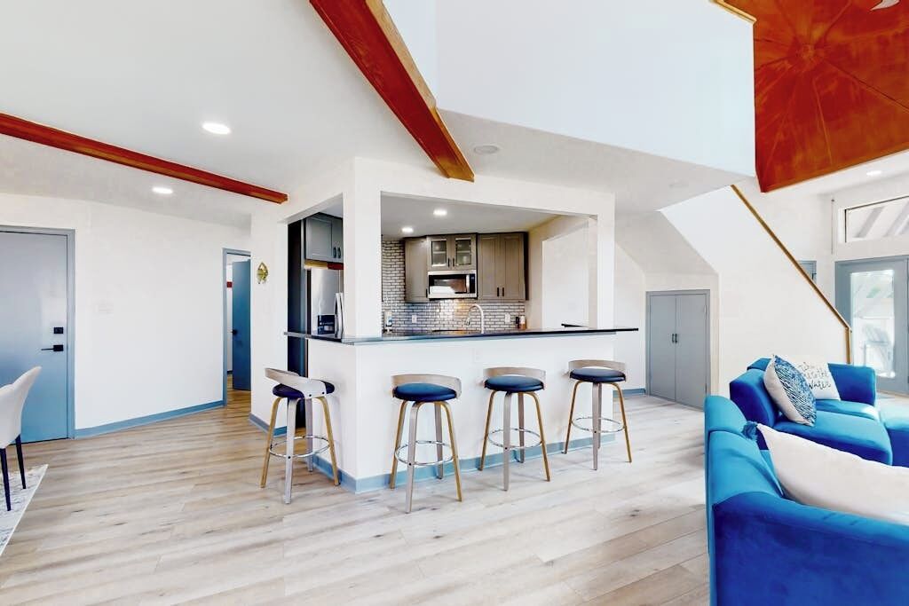 Un intérieur moderne avec un îlot de cuisine, des tabourets de bar et un canapé bleu.
