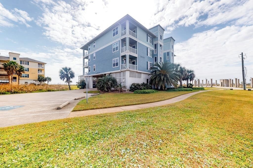 A multi-story residential building with a flat roof, balconies, and a landscaped lawn.