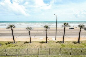 A beach view with palm trees, a road, and a car. - Dawn Condominiums - The Perfect Dawn (Galveston)