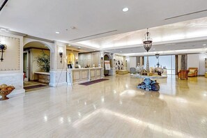 A spacious lobby with a marble floor, a reception desk, and a chandelier. - Infinity Sea of Serenity (Galveston)