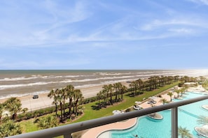A resort with a pool, beach view, and palm trees. - Infinity Sea of Serenity (Galveston)