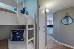 A bunk bed with a night sky-themed pillow, a white door, and a kitchen in the background. - Seahab, Maravilla Resort, Pools, Hot Tub, Beach (Galveston)