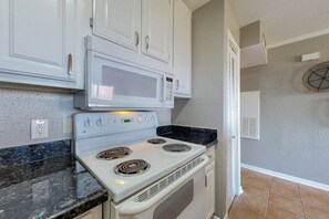 A kitchen with white cabinets, a microwave, and a stove. - Seahab, Maravilla Resort, Pools, Hot Tub, Beach (Galveston)