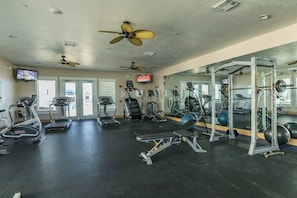 A gym with treadmills, elliptical machines, a weight bench, and a mirrored wall. - Pointe West Resort - OceanScape (Galveston)