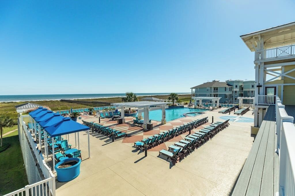 Een resort met een zwembad, ligbedden en uitzicht op de oceaan.