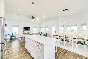 Una cocina amplia con una isla grande, piso de madera y un comedor con sillas y una mesa.