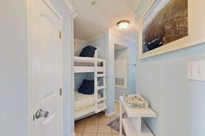 A narrow hallway with a bunk bed, a small table with books, and a framed picture on the wall. - Seascape Condos #1219 (Galveston)