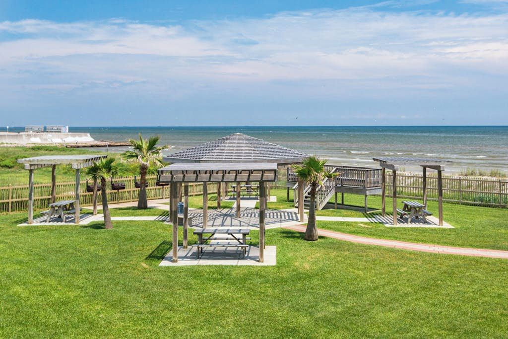 A beachside park with picnic tables, a gazebo, and a view of the ocean.