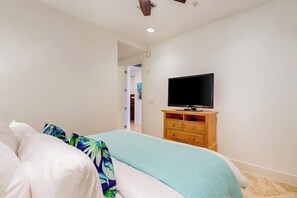 Un dormitorio con una cama, un televisor sobre un mueble de madera y una puerta que da a otra habitación.