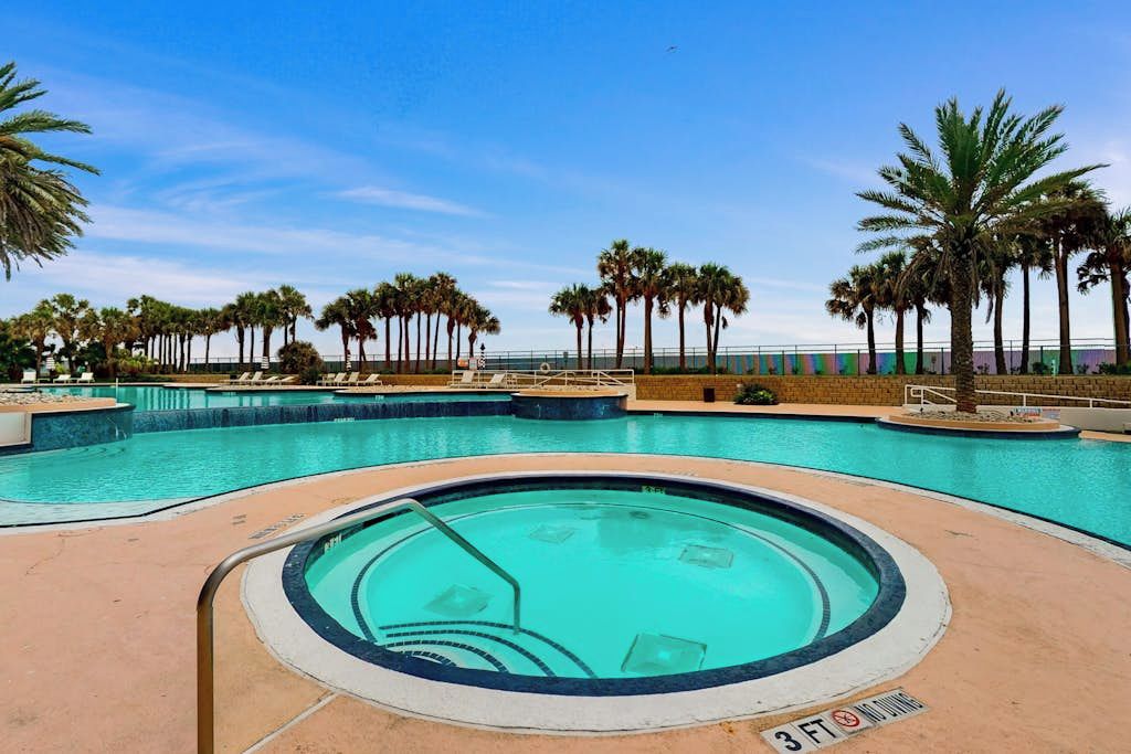 Une piscine dont la profondeur est indiquée à 3 pieds, entourée de palmiers et avec un ciel dégagé.